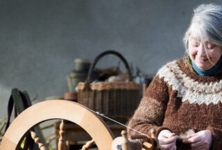 A lady spins yarn on a spinning wheel