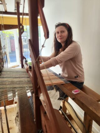 A lady sitting working at a loom A lady sitting working at a loom
