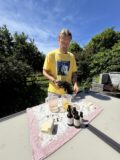 A man stands at a table holding seaweed. The table has ingredients for soap making