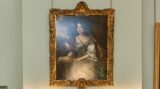 A portrait on a wall above an ornate fireplace