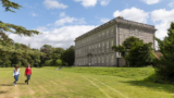 two people walking within the grounds of a manor house