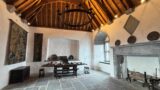 a room with a high wooden ceiling, and a dining table on a stone floor