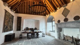 a room with a high wooden ceiling, and a dining table on a stone floor