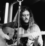 A young man plays a guitar