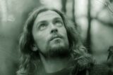 A long haired man looks upwards