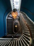 looking down onto a winding staircase, with a lantern-like light hanging above it