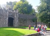 a group standing by medieval city walls receiving a tour